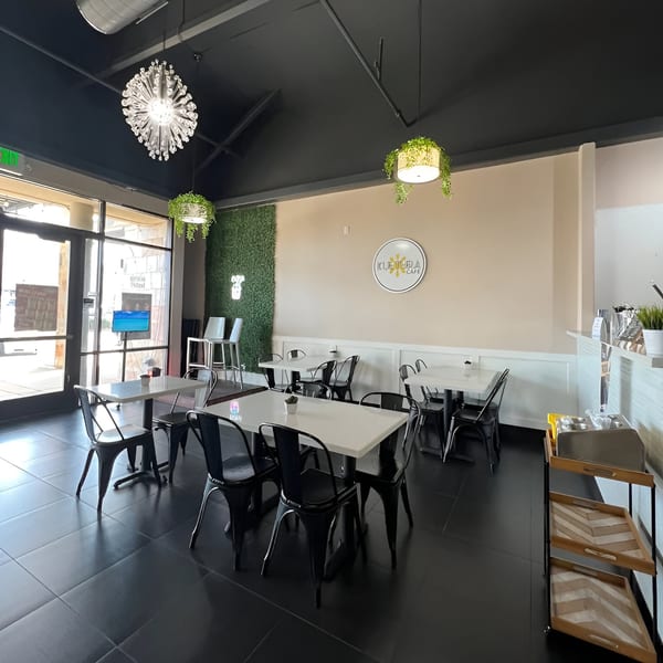 Interior of Kultura Cafe with black tables and chairs, a green wall, and the cafe's logo.