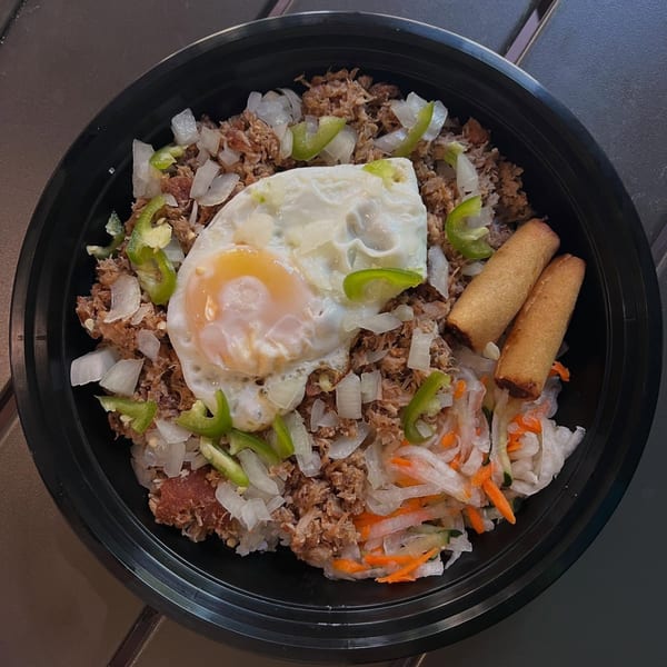 Filipino dish with shredded meat, fried egg, onions, green peppers, lumpia, and pickled vegetables.