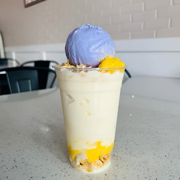 A Kultura Cafe halo-halo drink with ube ice cream, mango, and granola on a white counter.