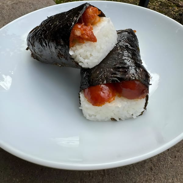Two Kultura Cafe spam musubi, with white rice and orange spam, wrapped in dark seaweed.