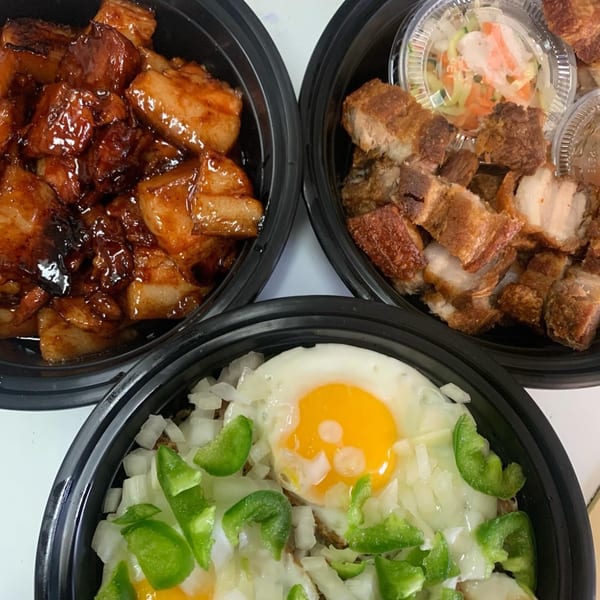 Three black bowls of Filipino food, including adobo, crispy pork belly, and a dish with fried eggs.